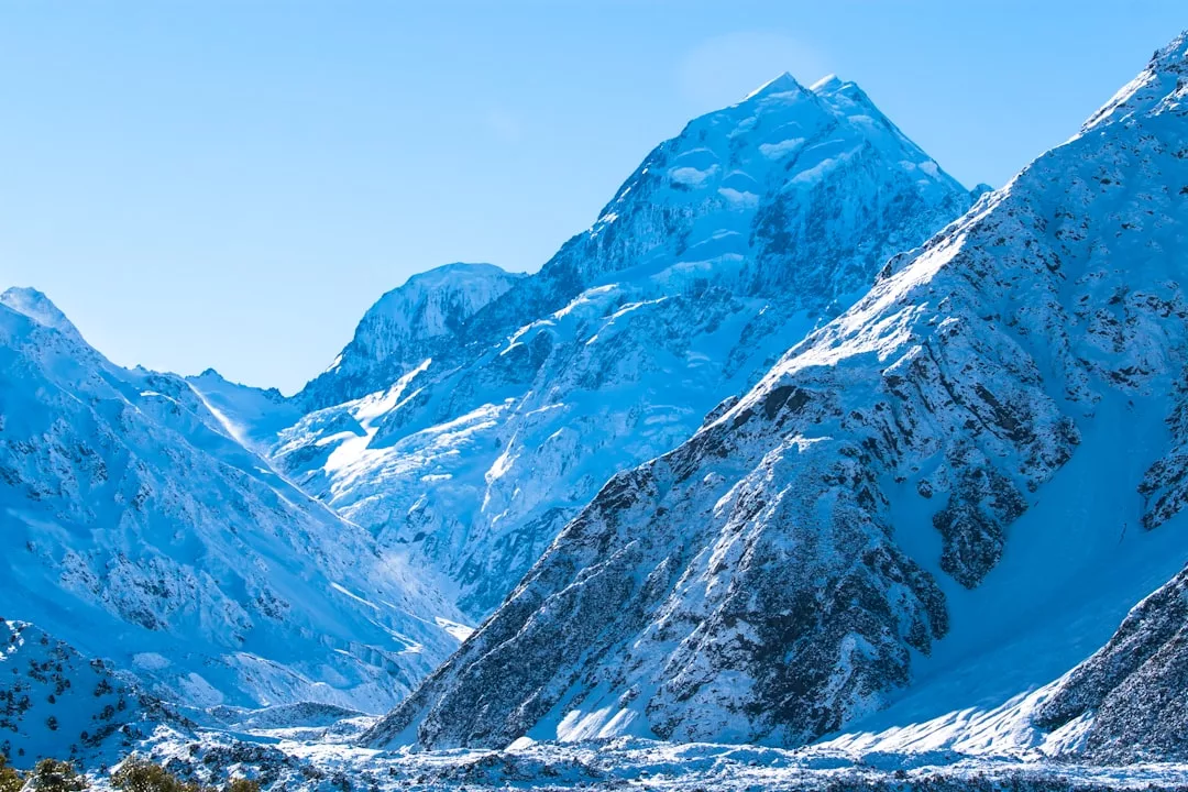 Snow-covered mountain peaks under a clear blue sky, with rugged slopes and a valley in the foreground—an idyllic scene capturing the essence of luxury living amidst nature’s grandeur.